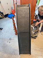 Full view of black plastic ribbed pet ramp standing upright