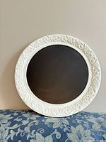 Front view of round chalkboard with ornate white frame