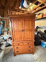 Front view of closed armoire showing paneled double doors, four lower drawers and mission hardware.