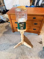 Full view of gumball machine on wooden stand in room