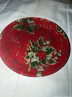 Top view of round red salad plate with Noel text and holly design
