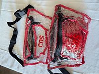 Both clear red-trimmed fanny packs showing straps and front pockets