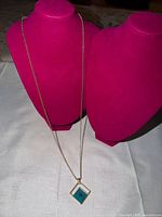 Full view of necklace draped on display busts showing overall length and pendant placement