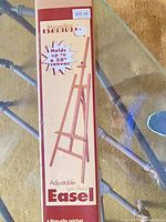 Front of boxed Marseilles Studios adjustable lyre floor easel