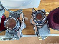 Minolta and Pentax SLR cameras with attached lenses in cases