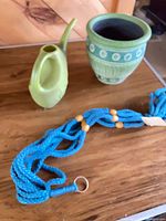 Overall view of ceramic pot, plastic watering can and teal macrame hanger
