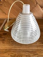 side view of ribbed white and clear glass pendant with cord and canopy