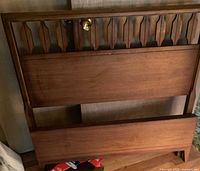 Wooden twin headboard and footboard leaning against wall
