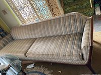 Full view of striped mid-century sofa against wall