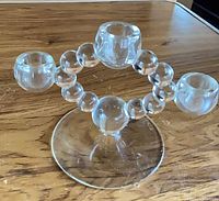 Single glass candelabra close-up showing bubble arms and three candle cups on round base