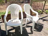 Two white resin patio chairs on deck