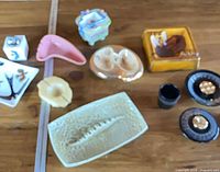 Group shot of all ten vintage ashtrays, lighters and holders on table