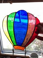 Hot-air-balloon stained-glass suncatcher held to light