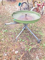 Full view of Structo avocado green charcoal grill on tripod stand with wheels