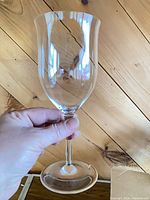 Hand holding single clear wine glass to show shape and clarity