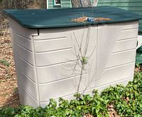 Beige plastic shed with green lid outdoors