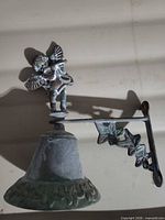 Side view of wall-mounted brass bell showing cherub finial and bracket