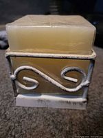 Front view of square ivory candle within distressed white metal holder