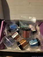 Seven pigment jars in plastic bags inside open box