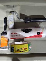 All four items laid out: roller frame, roller refill, brush, masking tape