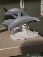 Front view showing three grey dolphins on white wave base