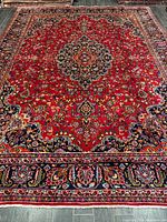 Full view of Mashhad rug showing red field, medallion, navy border