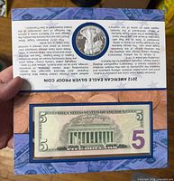 Display folder open showing $5 note and coin