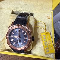 Watch in box showing dial, hang tag, protective plastics