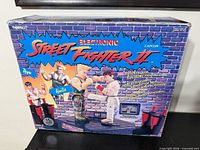 Front of boxed Tiger Street Fighter II game showing branding, figures, LCD display