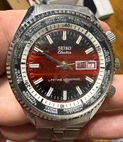 Front view showing red dial, world time bezel, day-date window