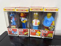 Front view of four boxed Simpsons bobble-heads
