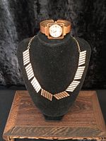 Necklace and bracelet watch displayed on bust and stand