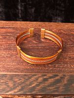 Oblique view of copper wire cuff on wood surface