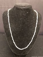 Necklace displayed on black velvet bust, showing full strand