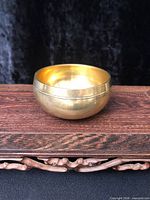 Side view of brass Tibetan singing bowl on wooden surface