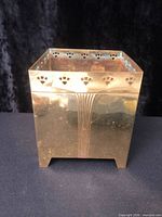 Front view of square brass box showing fluted panels and pierced rim