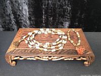 Long and bracelet malas displayed on wooden stand