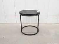 Full view of round metal side table showing legs and stretcher