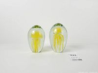 Front view of both glass paperweights showing jellyfish designs