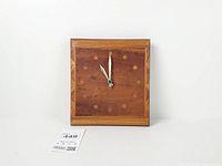 Front view of square inlaid wood wall clock showing face and hands