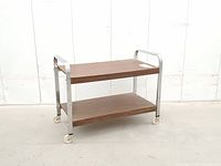 full side view of cart showing chrome frame, two woodgrain shelves, caster wheels