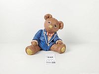 Front view of seated resin teddy bear coin bank showing jacket and bow tie