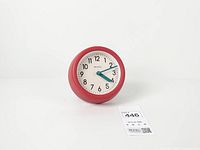 Front view showing red frame, dial, numerals and hands