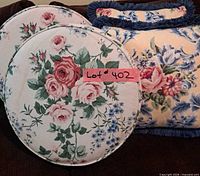 Two round floral cushions and one square floral pillow visible