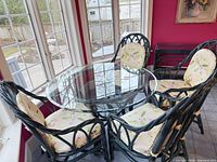 Round glass dining table with six rattan chairs around it