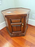 Front view of hexagonal wooden side table showing cabinet door and side drawers
