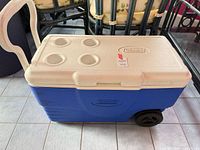 Closed cooler showing lid with four cup holders and wheel