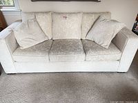 Front view of cream three-seat sofa with pillows