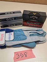 All five sealed golf ball boxes stacked with XL Redline glove pair visible