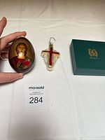 Group shot of egg ornament, glass cross ornament, green box